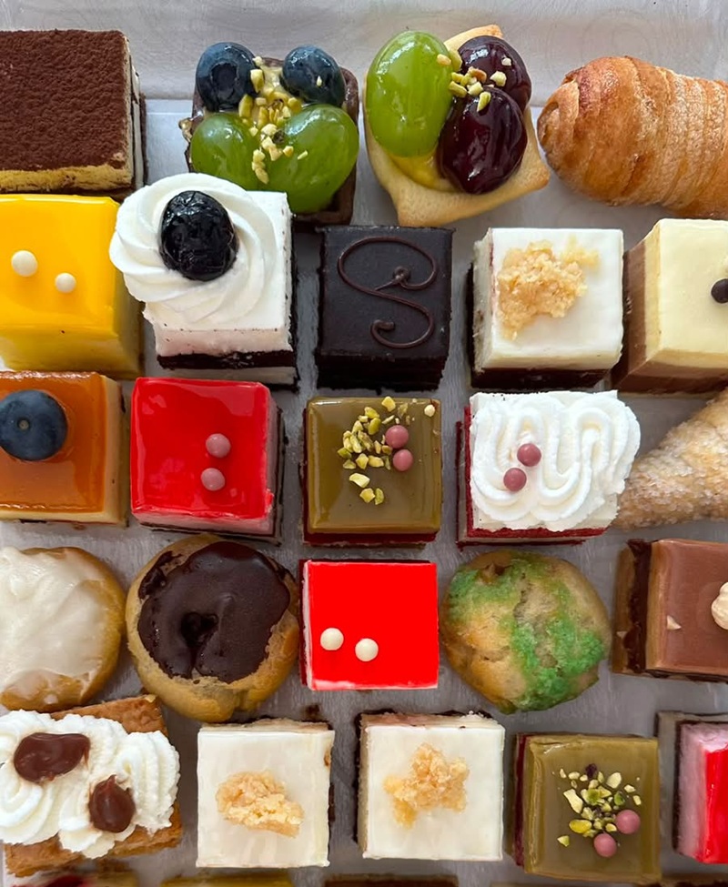 Piccola pasticceria Creo: cubetti glassati rossi, gialli e verdi, crostatine con uva e mirtilli, bignè e cannoncini